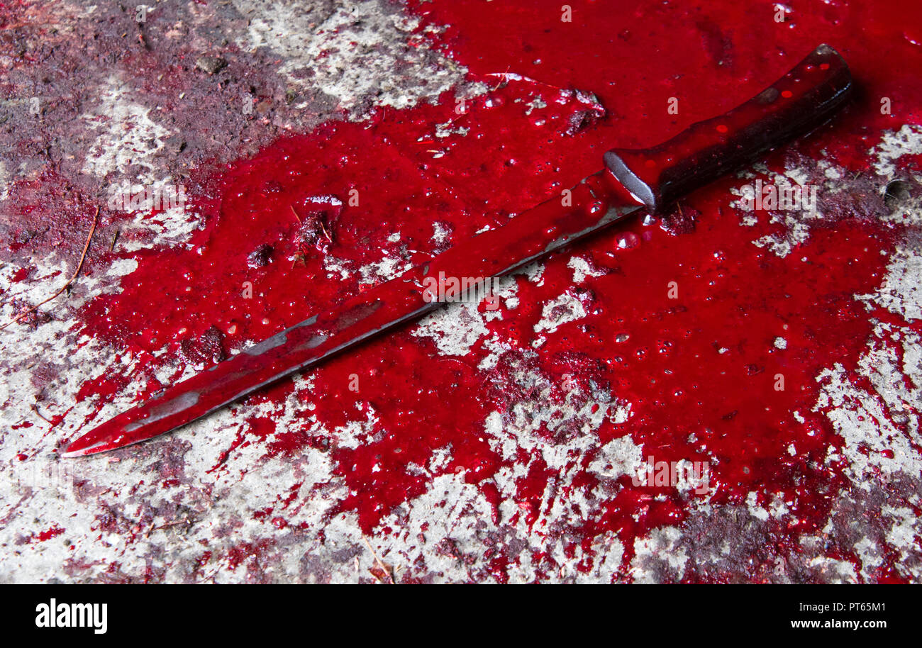 Image conceptuelle d'un couteau avec du sang sur elle repose sur un sol en béton. Photo Concept de meurtre et le crime Banque D'Images