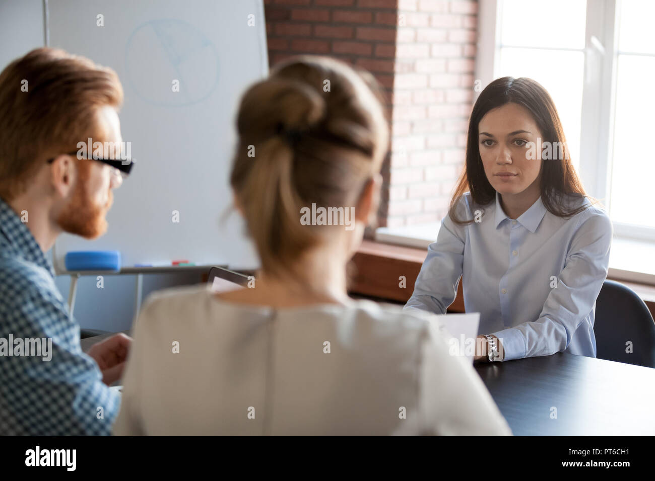 Femme sérieuse patron écoute des employés au sujet du travail de rapport Banque D'Images