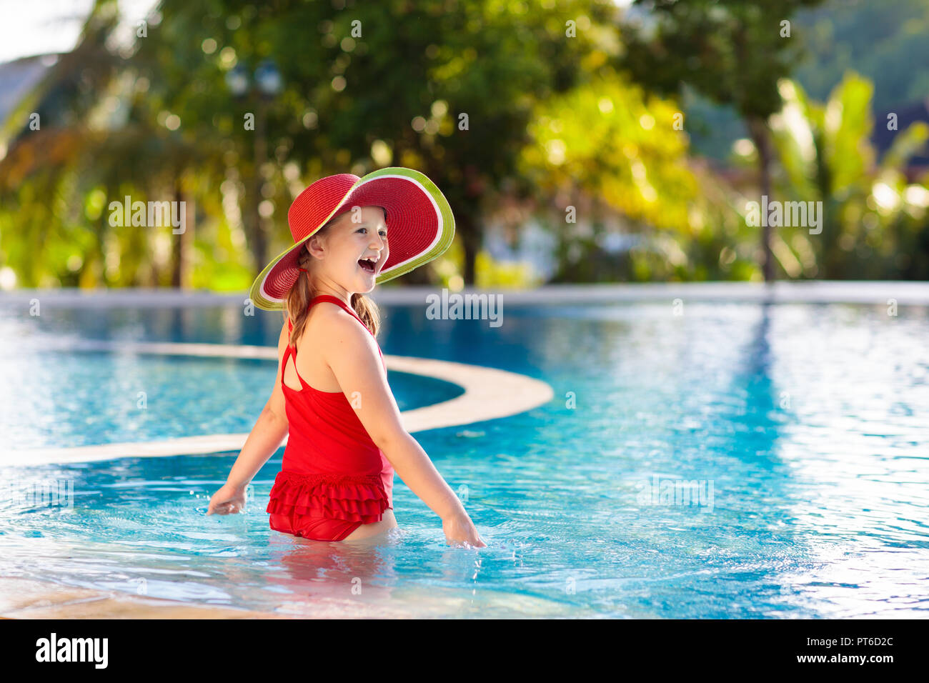 Enfant dans la piscine. Vacances tropicales pour les familles avec enfants.  Little girl wearing maillot rouge pastèque et chapeau de soleil jouant dans  la piscine extérieure de l'exo Photo Stock - Alamy