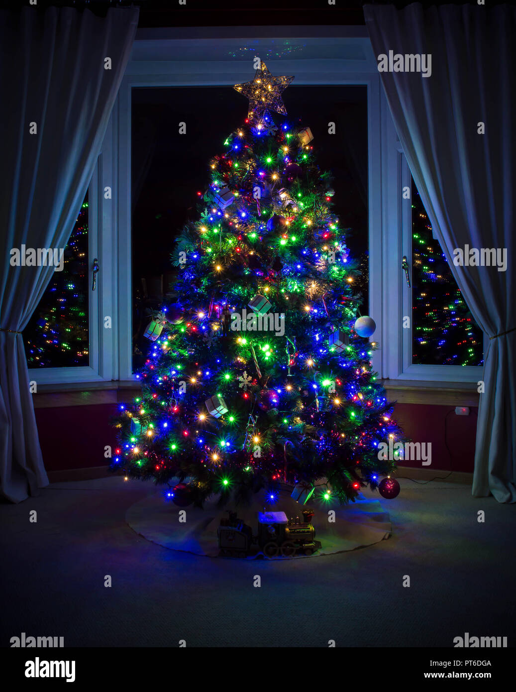 Arbre de Noël dans une fenêtre avec des lumières colorées Banque D'Images