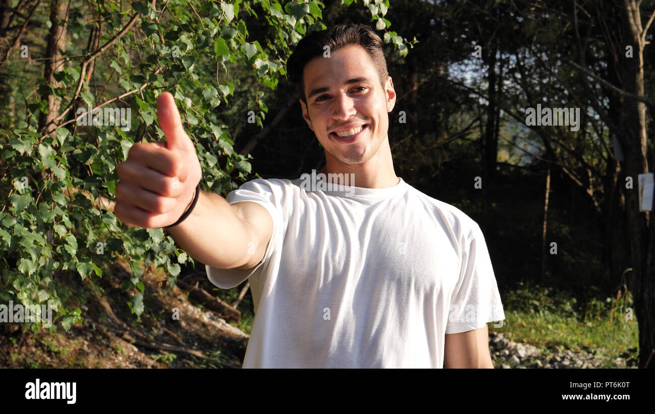 Jeune homme dans la nature faisant thumb up Banque D'Images