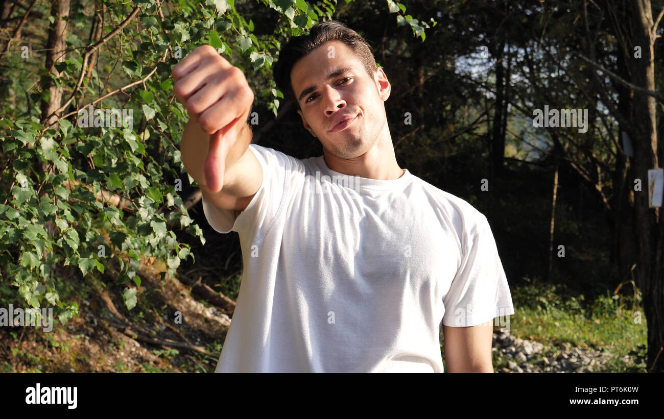 Jeune homme en faisant signe du pouce vers le bas de la nature Banque D'Images