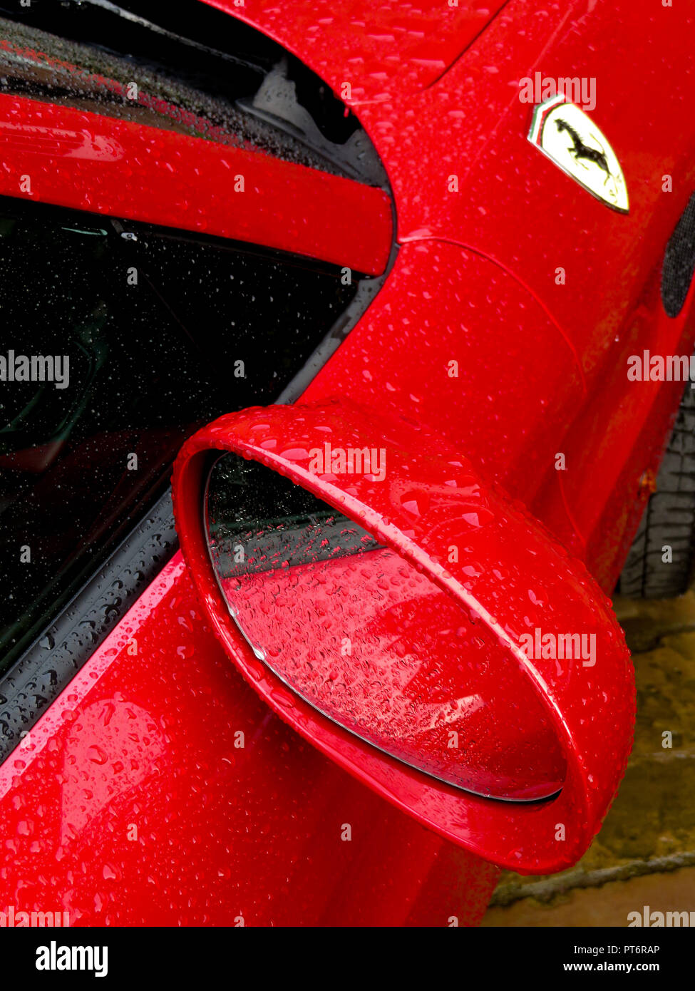 Le rétroviseur et le logo Ferrari sous la pluie montrant une carrosserie d'au-dessus Banque D'Images