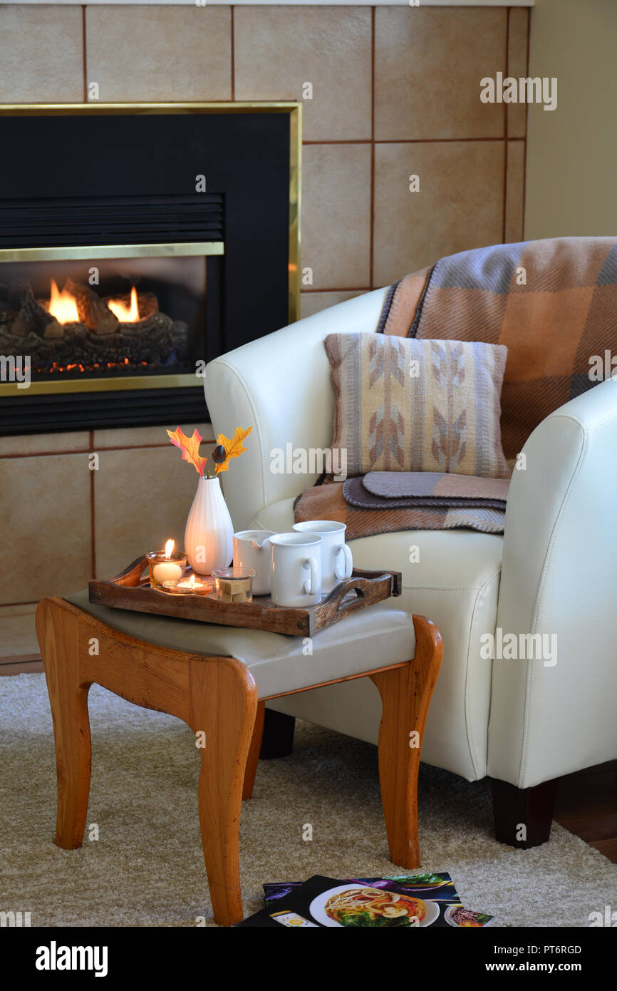 Hygge home comfort avec godet souple en cuir chaise, bougies, couverture et  un plateau à côté d'une cheminée à gaz. Format vertical de lumière  naturelle Photo Stock - Alamy