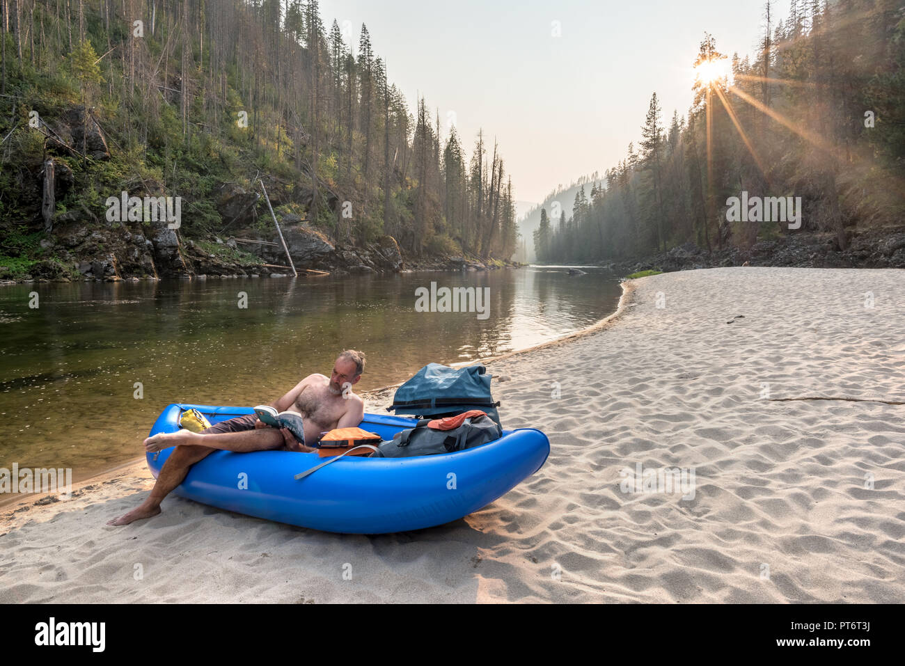 River Runner la lecture et de détente dans un kayak gonflable sur une plage le long de la rivière de l'Idaho de Selway. Banque D'Images