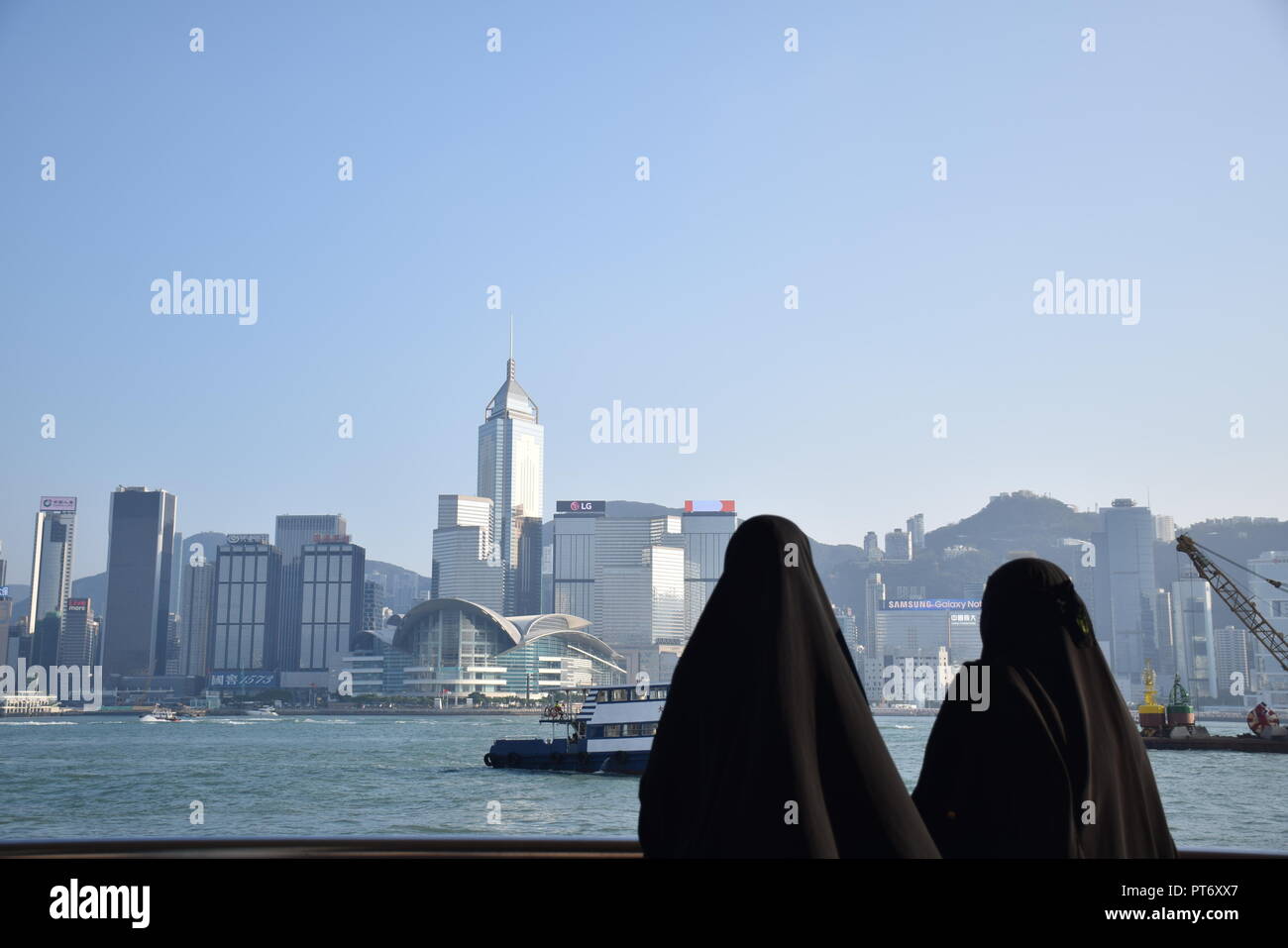 Les filles habillées avec burqa en face de la skyline de l'île de Hong Kong à partir de la promenade de Tsim Sha Tsui à Hong Kong, Chine Banque D'Images
