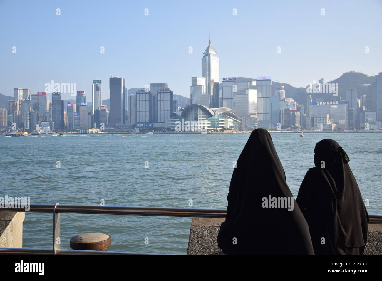 Les filles habillées avec burqa en face de la skyline de l'île de Hong Kong à partir de la promenade de Tsim Sha Tsui à Hong Kong, Chine Banque D'Images