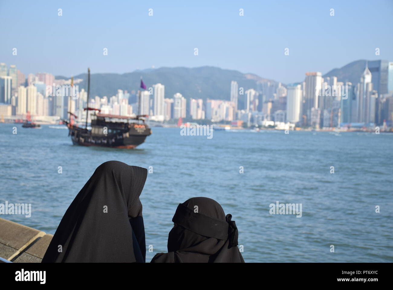 Les filles habillées avec burqa en face de la skyline de l'île de Hong Kong à partir de la promenade de Tsim Sha Tsui à Hong Kong, Chine Banque D'Images