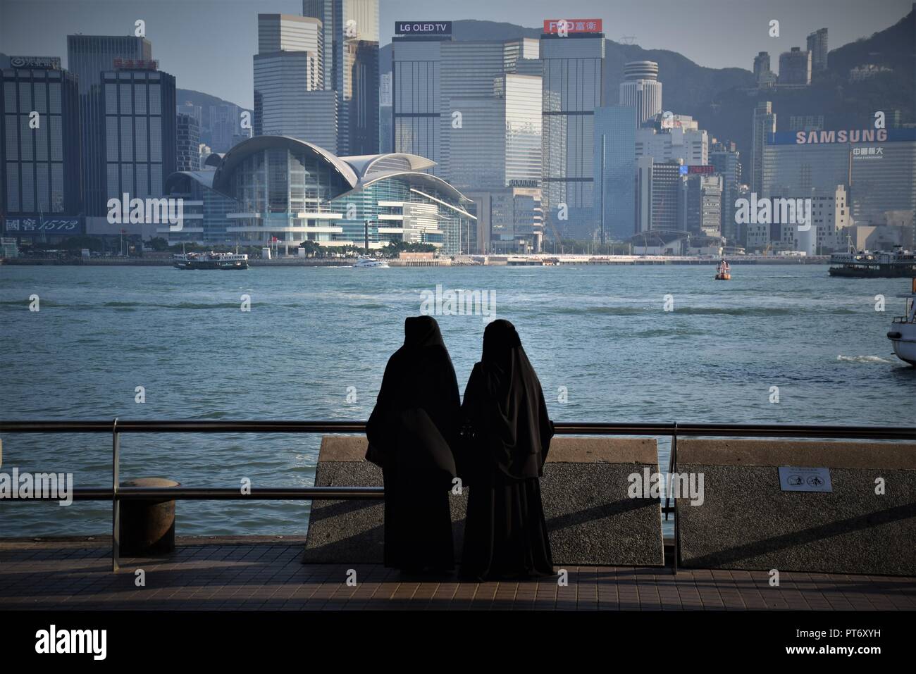 Les filles habillées avec burqa en face de la skyline de l'île de Hong Kong à partir de la promenade de Tsim Sha Tsui à Hong Kong, Chine Banque D'Images