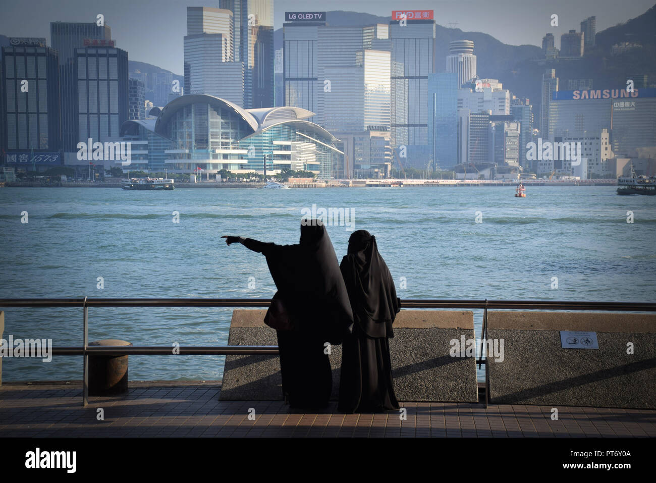 Les filles habillées avec burqa en face de la skyline de l'île de Hong Kong à partir de la promenade de Tsim Sha Tsui à Hong Kong, Chine Banque D'Images