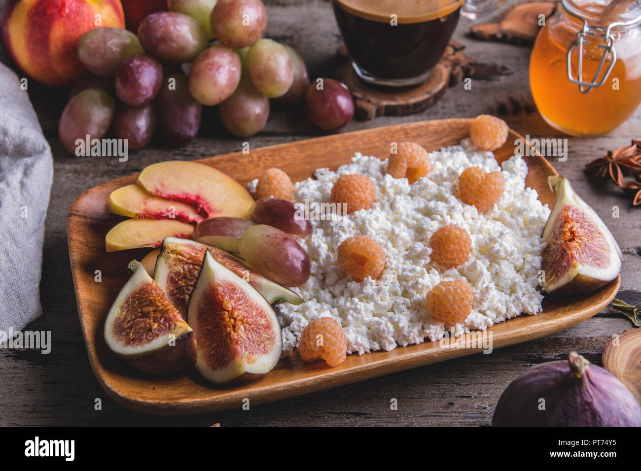 Le fromage cottage ,,framboises figues , pêche, miel. Un petit-déjeuner sain, café. sur le service à bord plus rustique en Banque D'Images