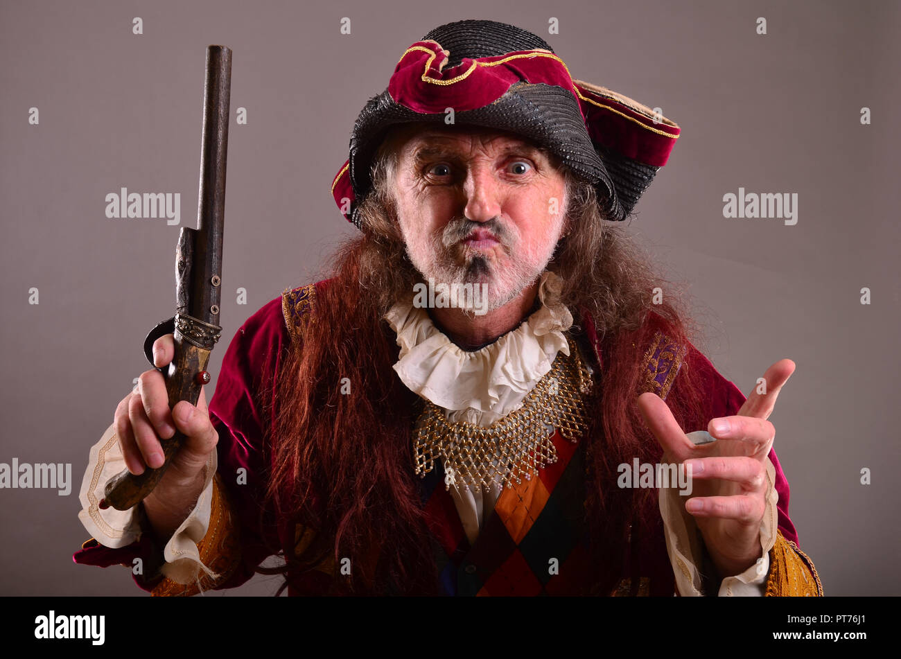 Vieux pirate est en colère, exige de l'attention par l'expression visage et discours, agitant la main par le canon Banque D'Images