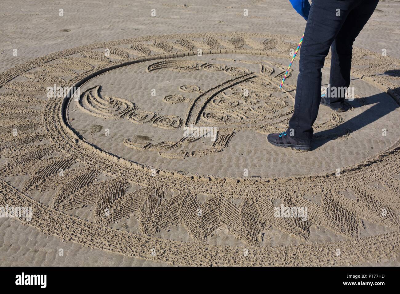 Un bénévole travaillant dans un grand labyrinthe de sable créé par Denny Dyke, à Florence en plage Heceta, Oregon, USA. Banque D'Images