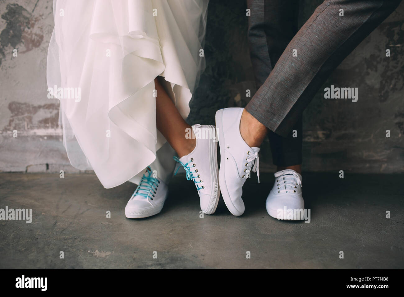 Hommes et femmes recadrée jambes wearing white sneakers. Mariage dans sneakers Banque D'Images
