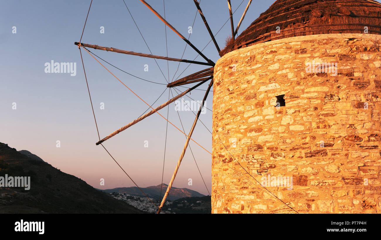 Un vieux moulin en pierre au sommet d'une montagne, dans le contexte d'une chaîne de montagnes et la vallée avec une petite ville aux maisons blanches sur une île grecque Banque D'Images