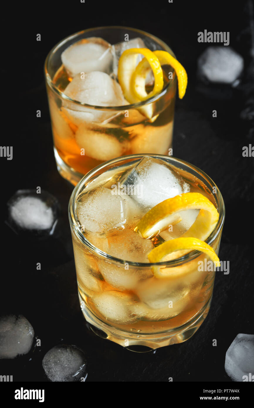 Whiskey ou de rhum sur les roches avec de citron sur fond noir en noir. Banque D'Images