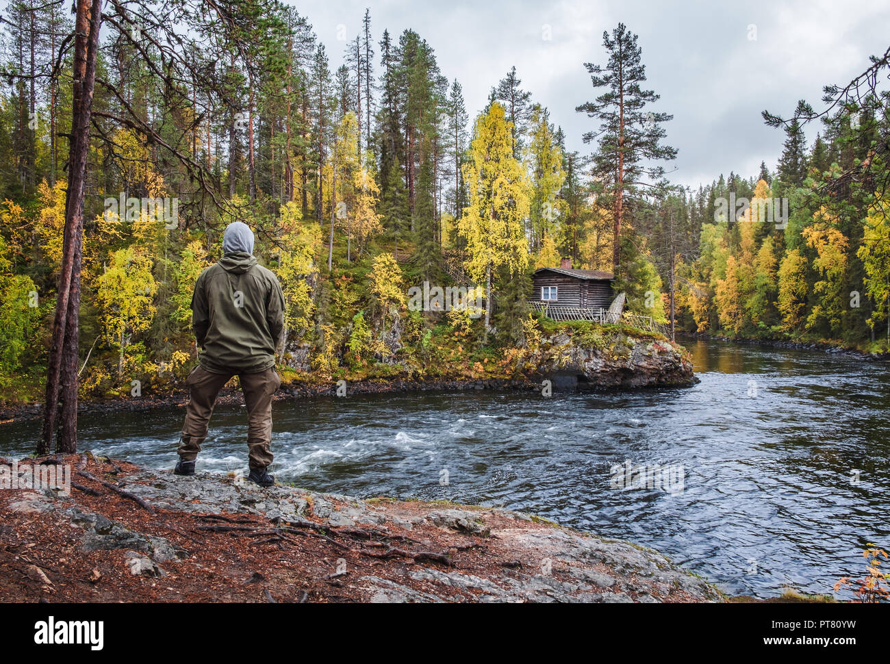 Homme debout devant de très belle forêt avec couleurs d'automne et vieux chalet au jour de l'humeur de Myllykoski, Kuusamo, Finlande Banque D'Images