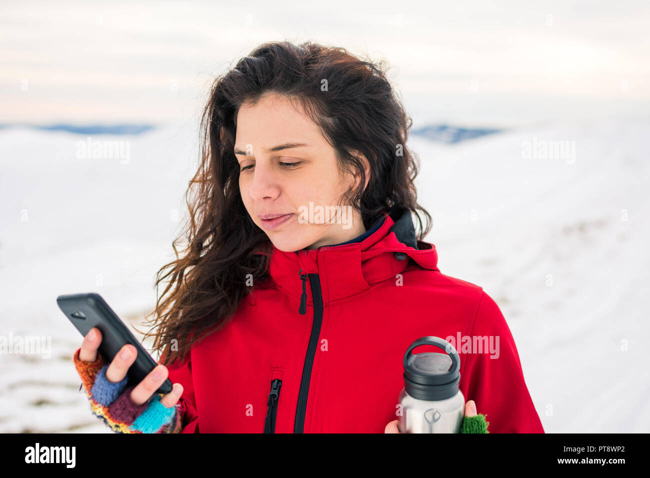 Femme à l'aide de téléphone sur un sommet de montagne couverte de neige Banque D'Images