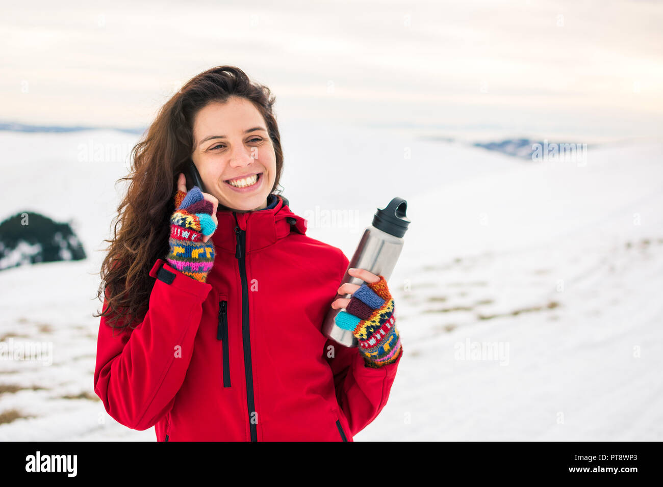 Femme à l'aide de téléphone sur un sommet de montagne couverte de neige Banque D'Images