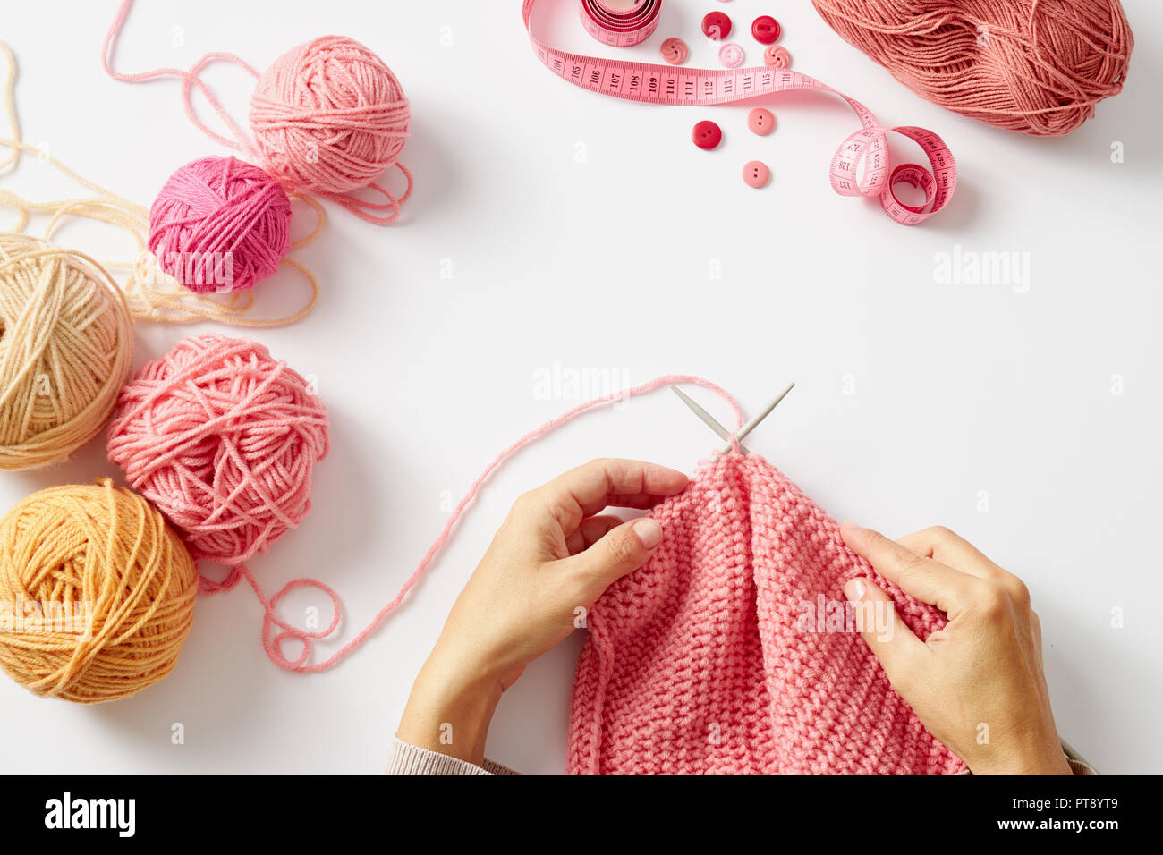 Les mains des femmes avec tricot de laine rose, sur un fond blanc, vue du dessus Banque D'Images