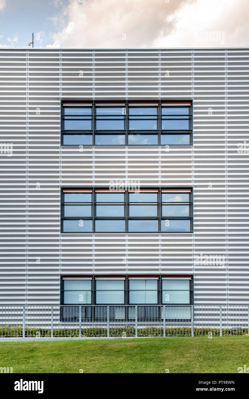 Vue symétrique d'un bâtiment commercial moderne avec trois grandes fenêtres larges et une pelouse verte en face Banque D'Images