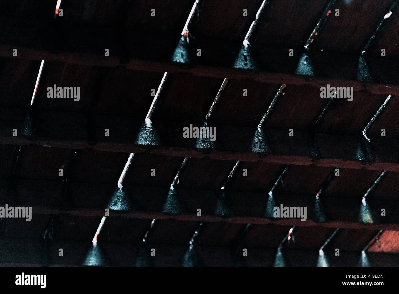 Des faisceaux de lumière qui brille à travers fissures entre un plancher de bois sombre du dessous Banque D'Images