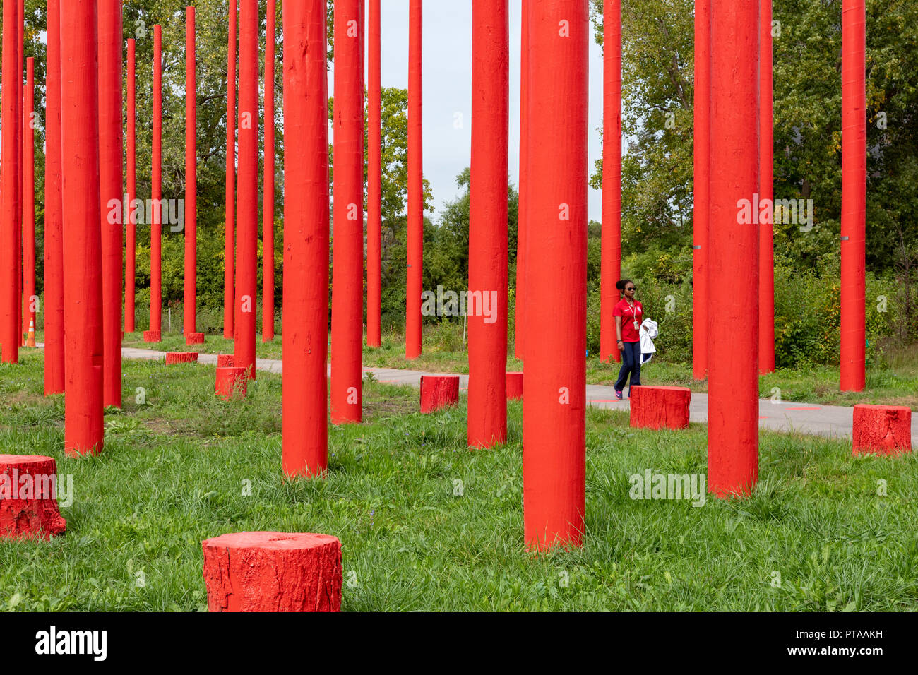 Southfield, Michigan - une femme marche à travers le parc, un pôle rouge public art project a créé avec de vieux poteaux électriques et les souches d'arbre. Banque D'Images