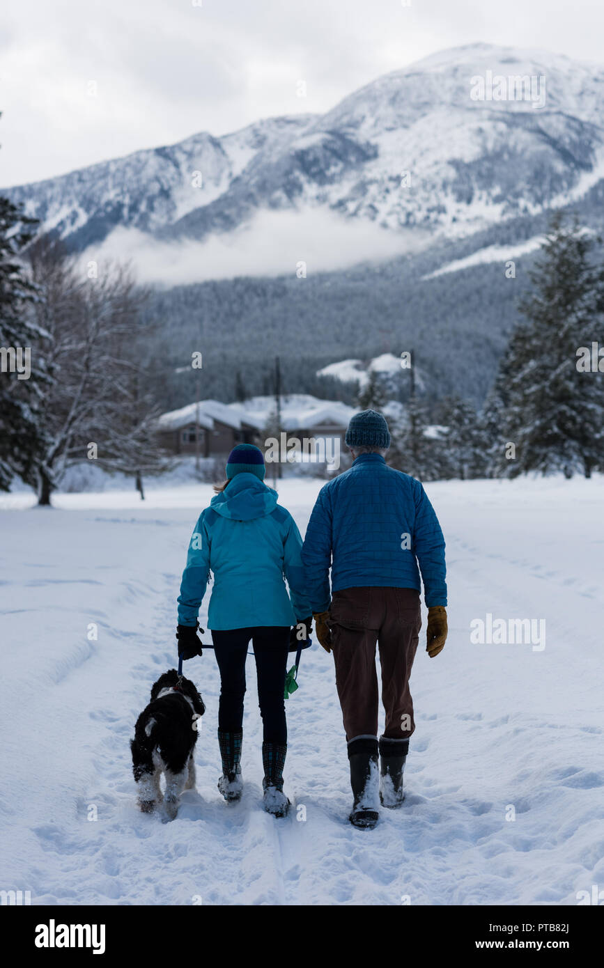 Couple avec dog walking on snow landscape Banque D'Images