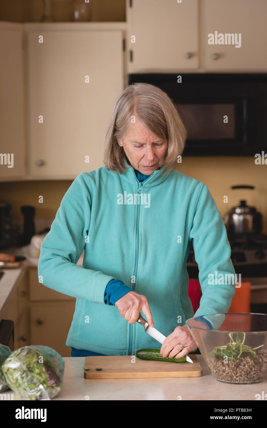 Senior woman cutting concombre avec le couteau à découper Banque D'Images