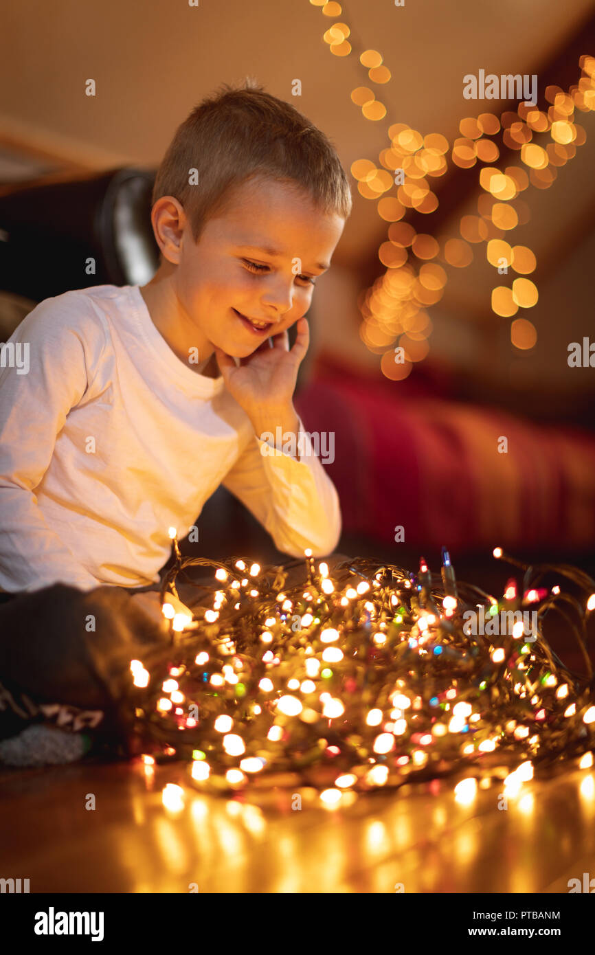 Boy looking at fairy lights éclairés à la maison Banque D'Images