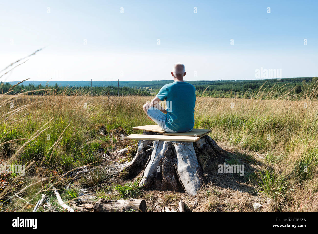 Homme assis vous détendre sur un arbre et le yoga dans la forêt de la Belgique parc naturel des Ardennes Banque D'Images