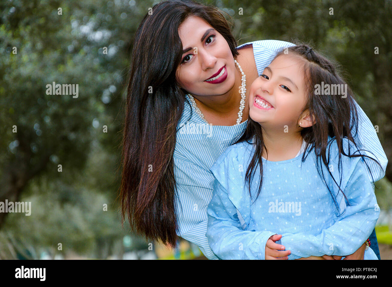 Mère portant son joli sourire et sa fille dans le parc sur un après-midi d'hiver Banque D'Images