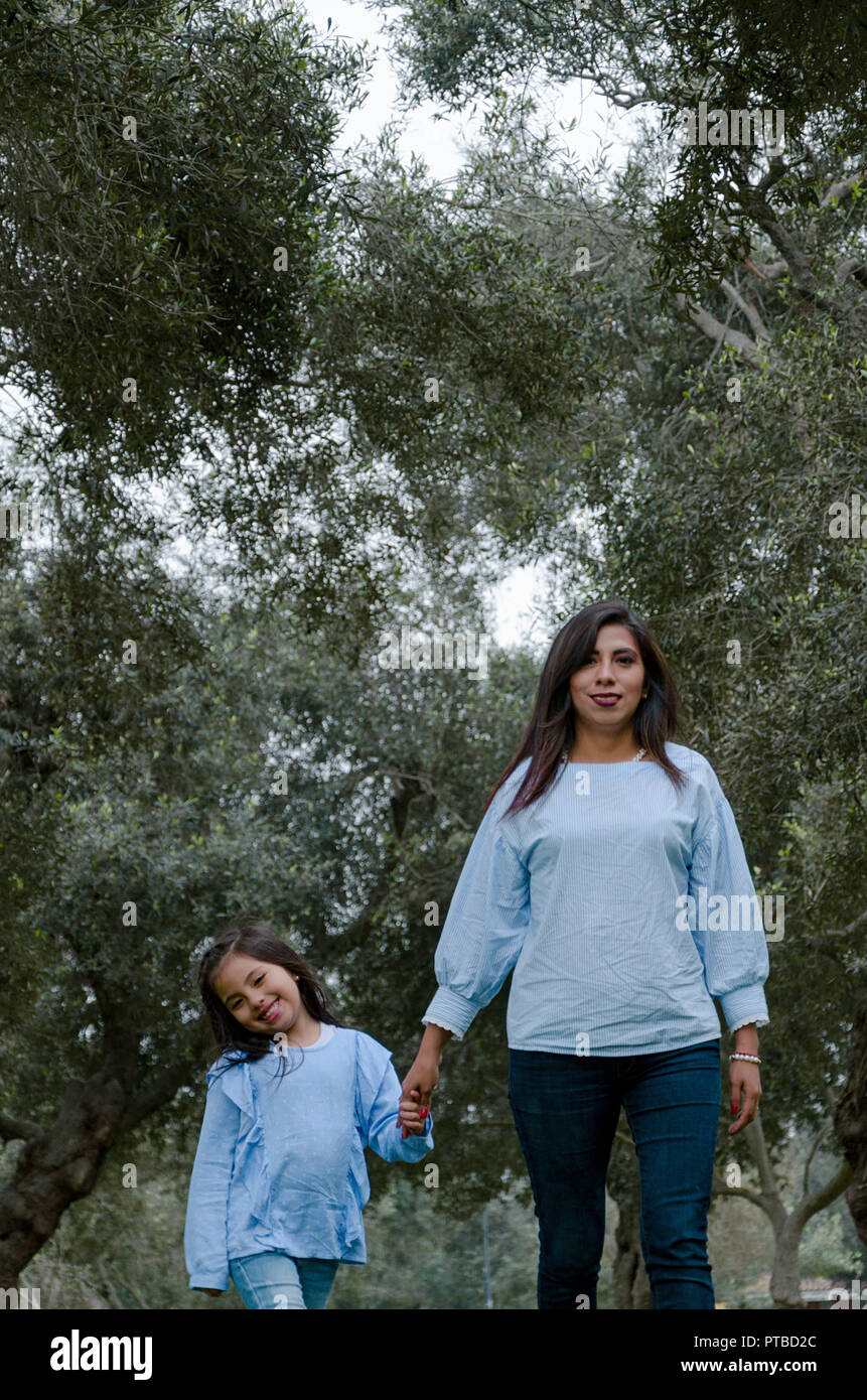 Mère et fille péruvienne peu marcher ensemble dans le parc sur un après-midi d'automne Banque D'Images
