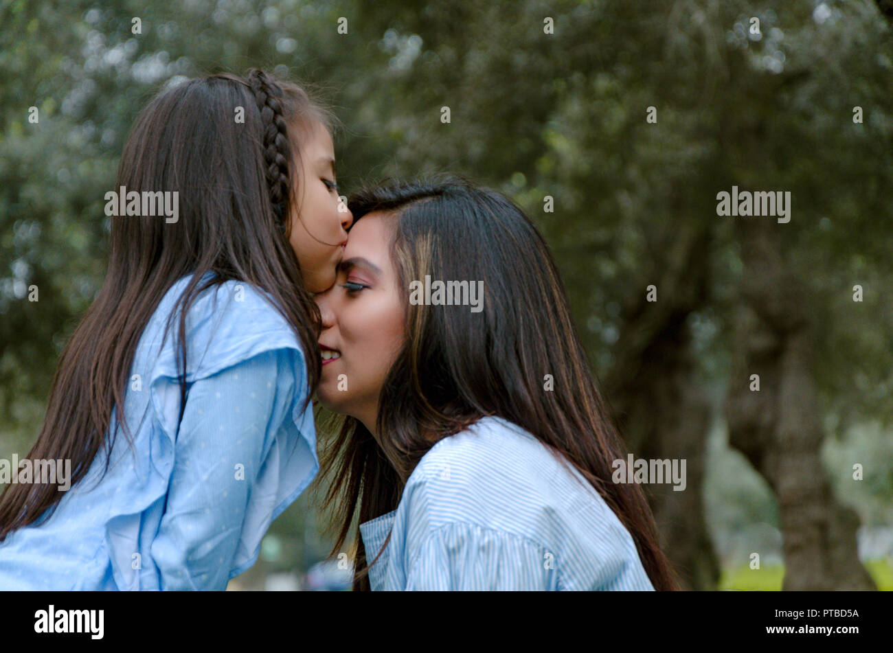 Heureux fille embrasser mère bénéficiant d'un après-midi d'hiver dans le parc Banque D'Images