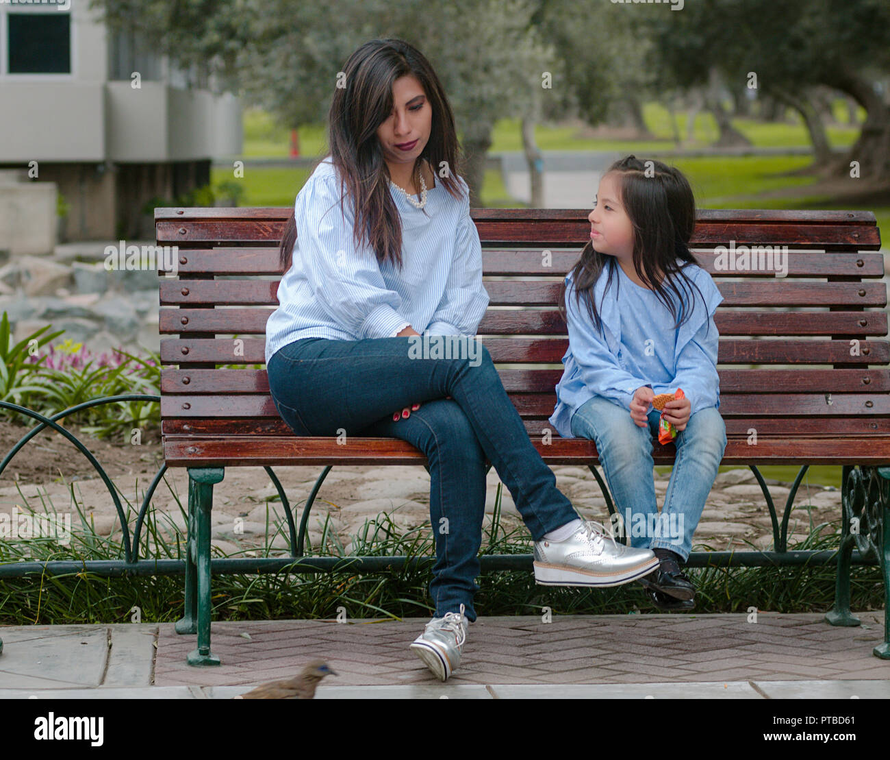 Mère et sa petite fille assise sur un banc dans le parc Banque D'Images