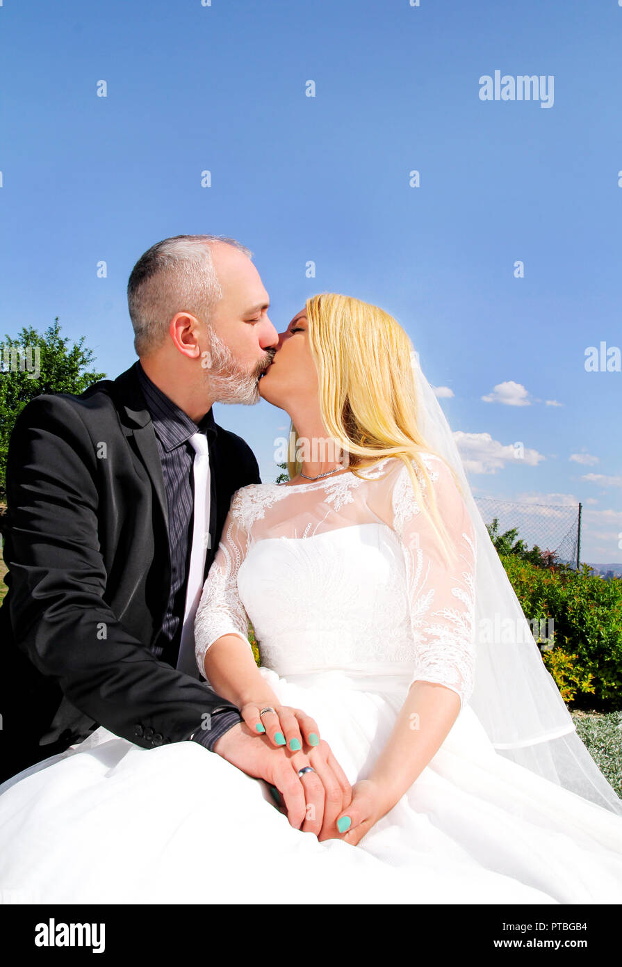 Concept de mariage. L'heureux couple de mariage beau sont assis et s'embrasser. Le marié et la mariée dans l'amour. En arrière-plan est magnifique. Banque D'Images