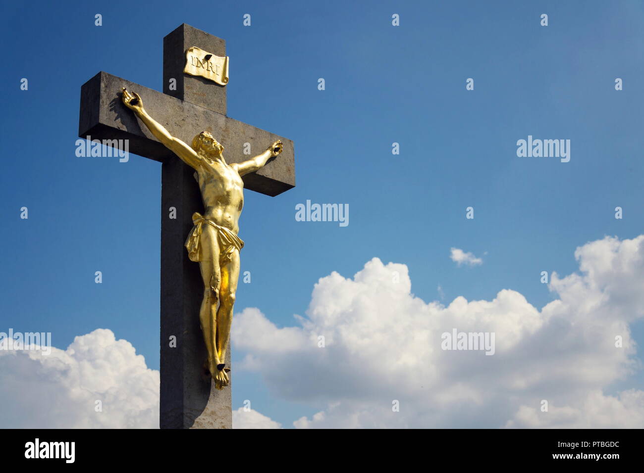 Golden Jésus Christ crucifixion statue, journée ensoleillée fond de ciel bleu, Vrbice, Moravie, République Tchèque Banque D'Images