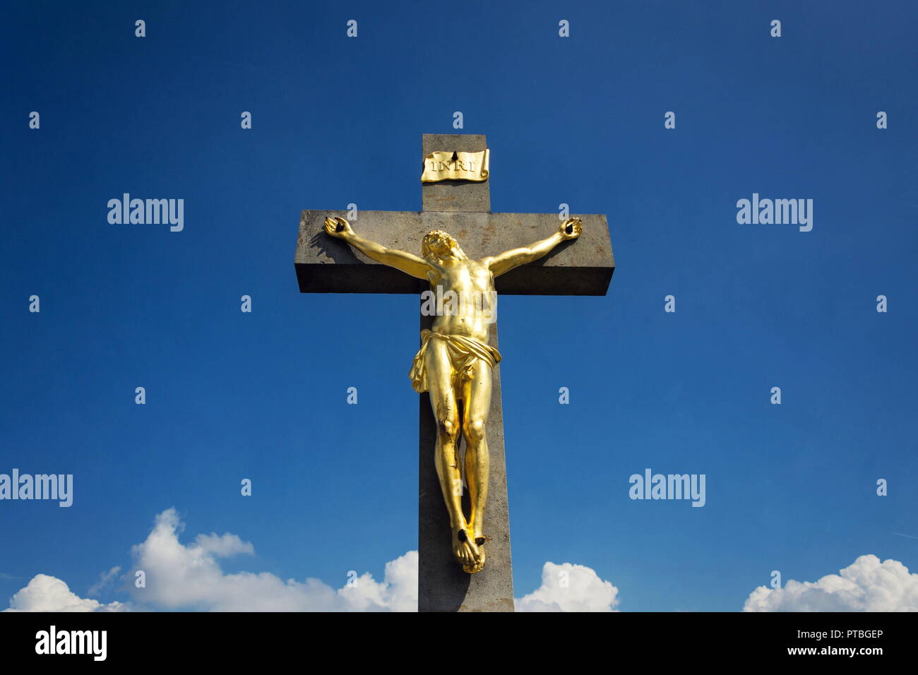 Golden Jésus Christ crucifixion statue, journée ensoleillée fond de ciel bleu, Vrbice, Moravie, République Tchèque Banque D'Images
