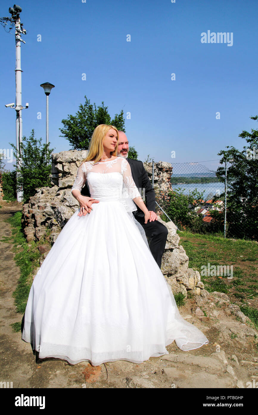 Concept de mariage. L'heureux couple de mariage beau sont assis et à la recherche. Le marié et la mariée dans l'amour. En arrière-plan est magnifique. Banque D'Images