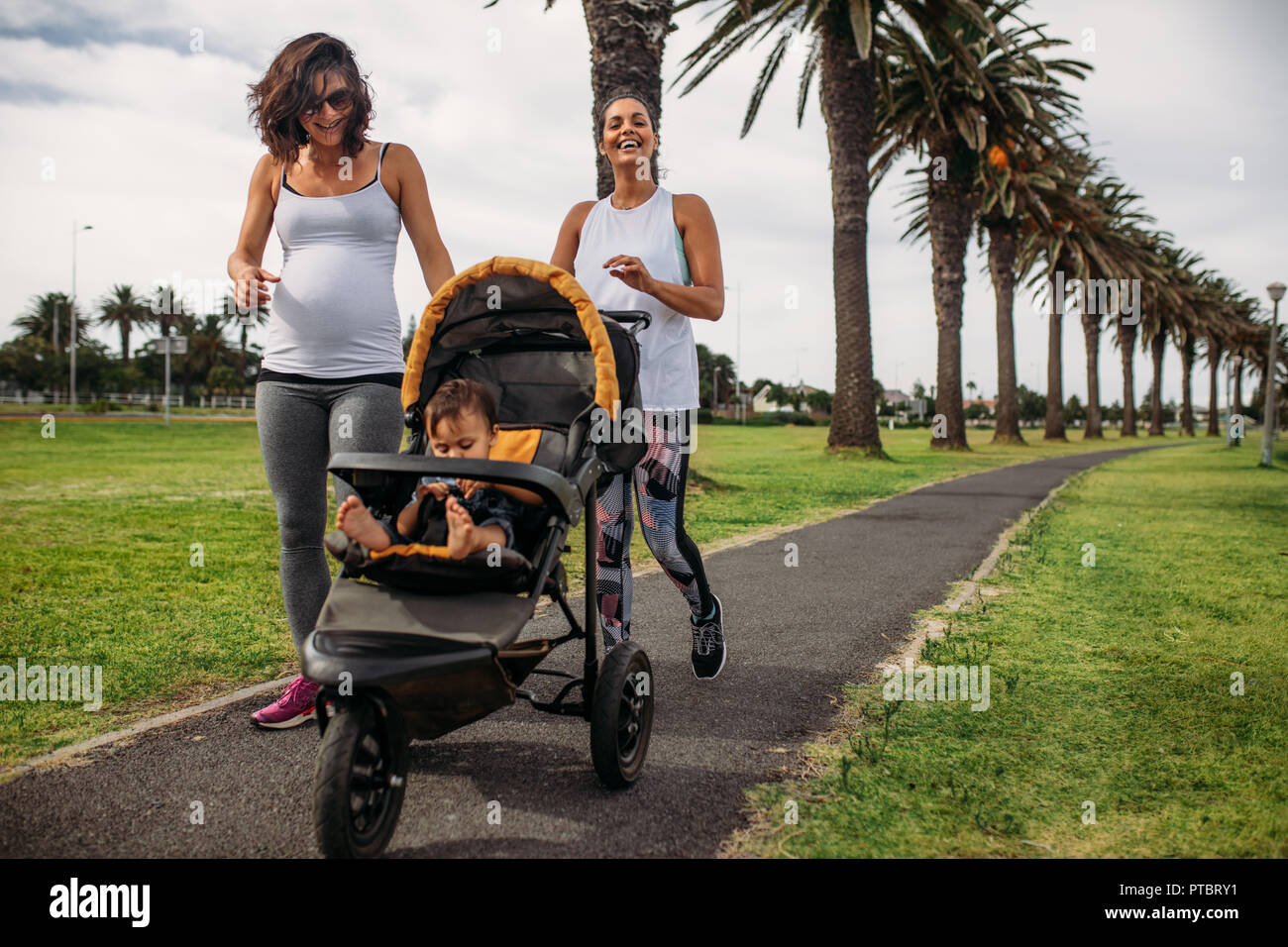 Deux Femmes Marchant Avec Un Bebe Landau Dans Un Parc Femme Enceinte Sur Une Marche Matinale Avec Son Bebe Dans Une Poussette Photo Stock Alamy