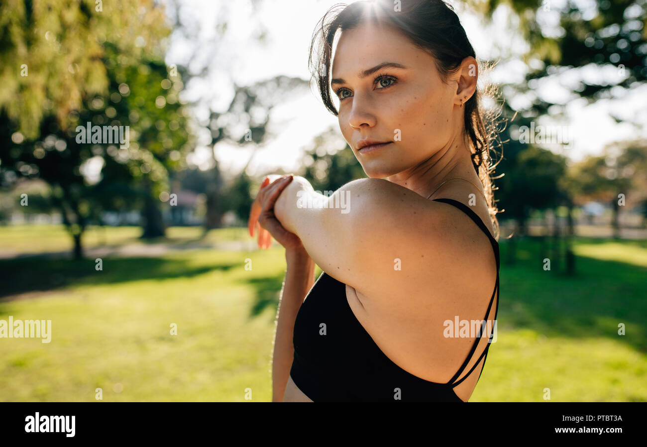 Close up of young woman l'échauffement avant une course à l'extérieur. Coureuse faisant des exercices d'étirement en matinée au parc. Banque D'Images