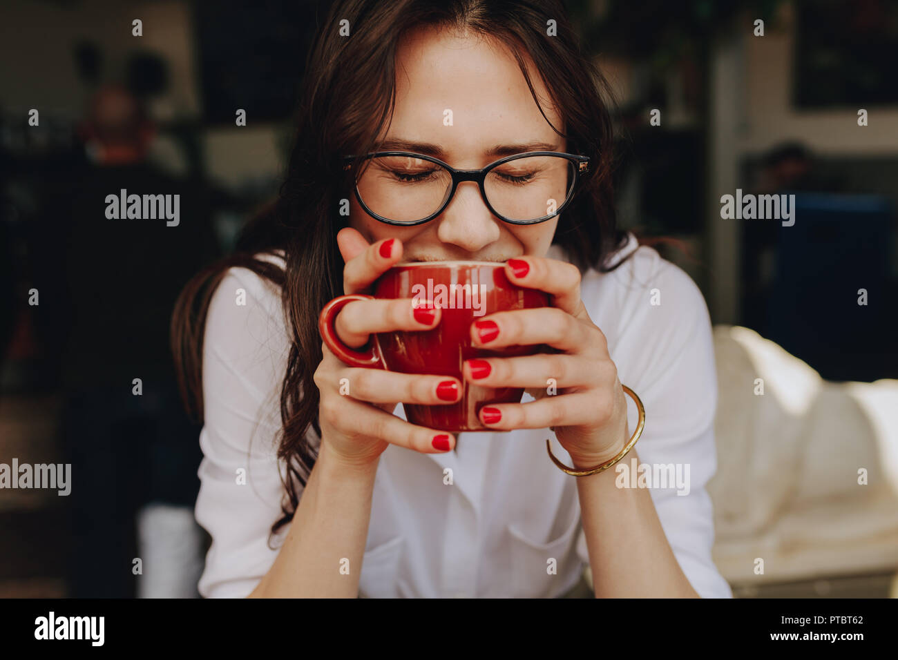 Portrait de femme à lunettes tenant une tasse à café. Woman smelling l'arôme de café au café avec ses yeux fermés. Banque D'Images
