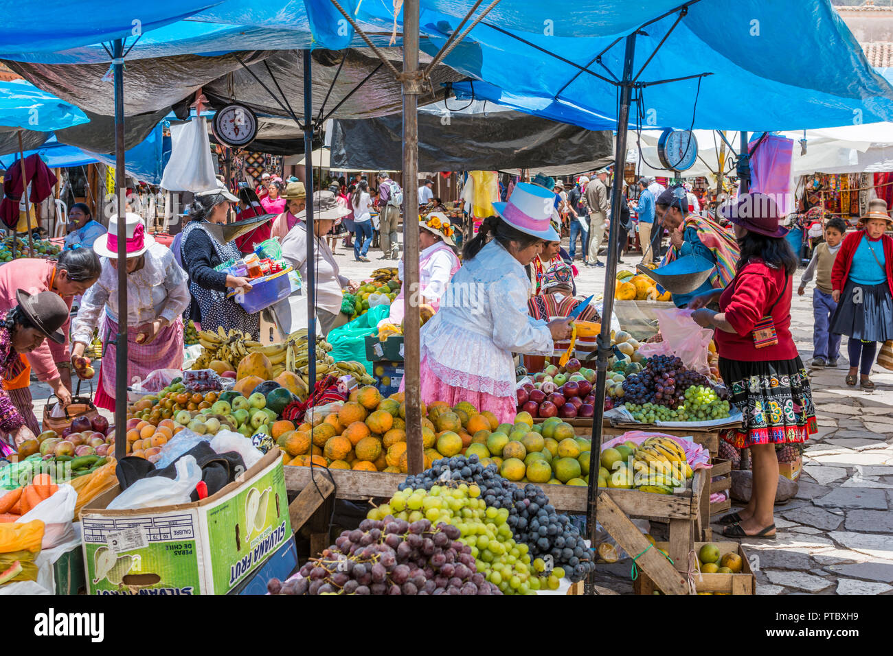 Pérou femmes en vêtements traditionnels colorés et des chapeaux de vendre des fruits et des légumes au marché du dimanche à Pisac, Pérou, Amérique du Sud. Banque D'Images