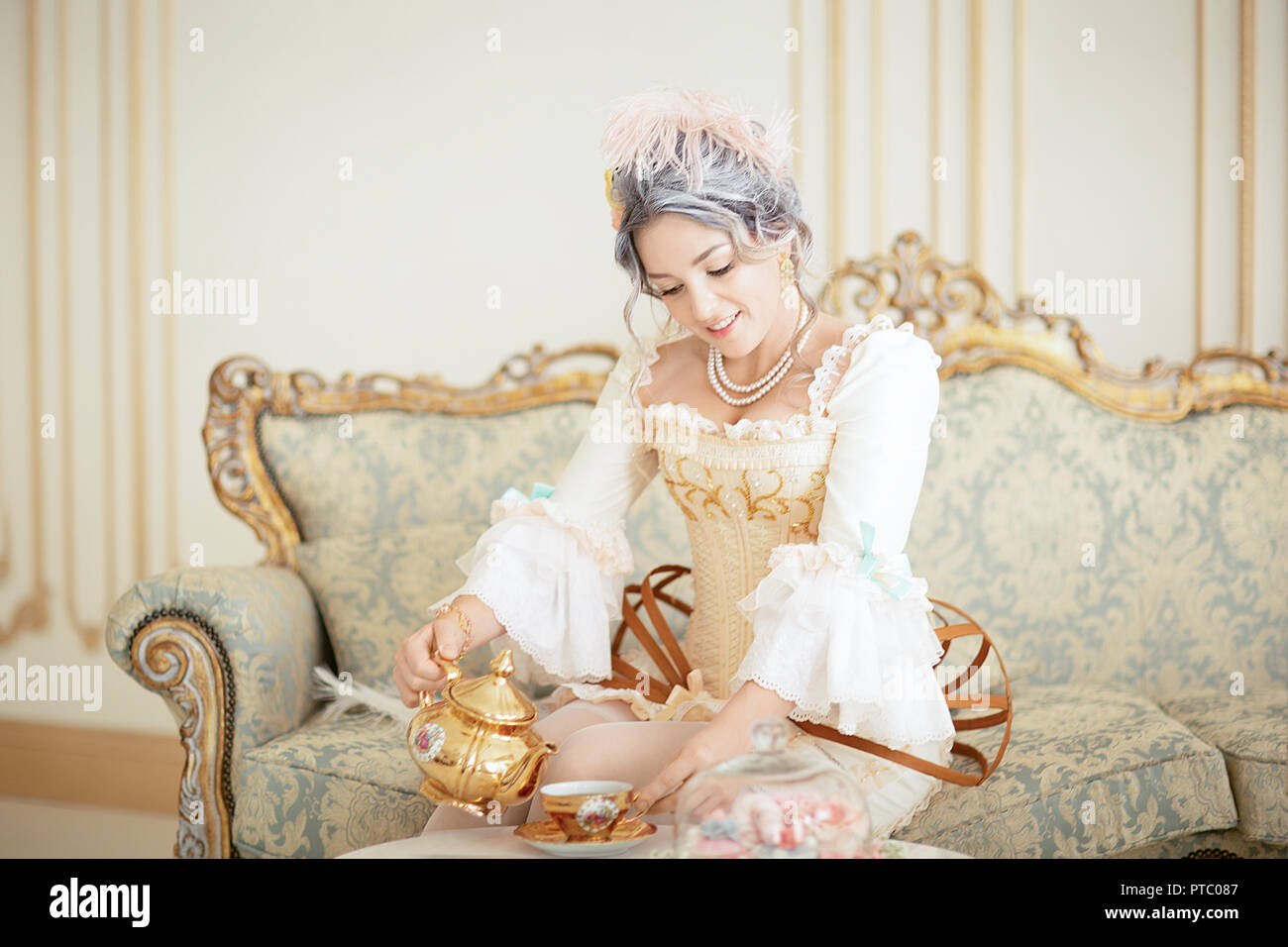 Belle femme grayhead en robe Rococo posant devant fond rose en versant le thé de l'électrique, le déjeuner. L'halloween Banque D'Images