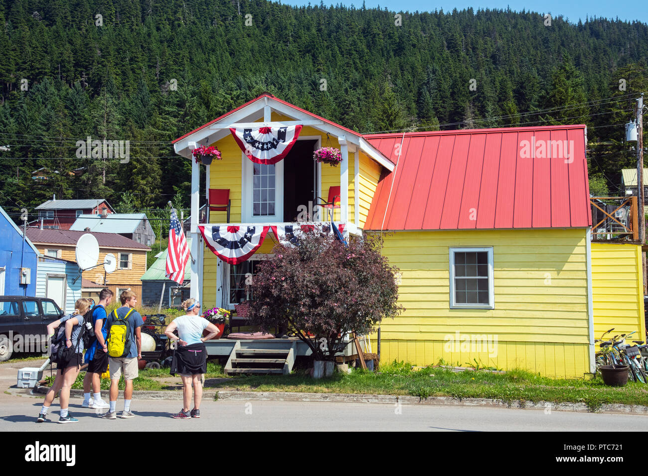 Groupe d'admirer des maisons en bois colorées avec drapeaux, Amecan Hoonah, Alaska, USA Banque D'Images