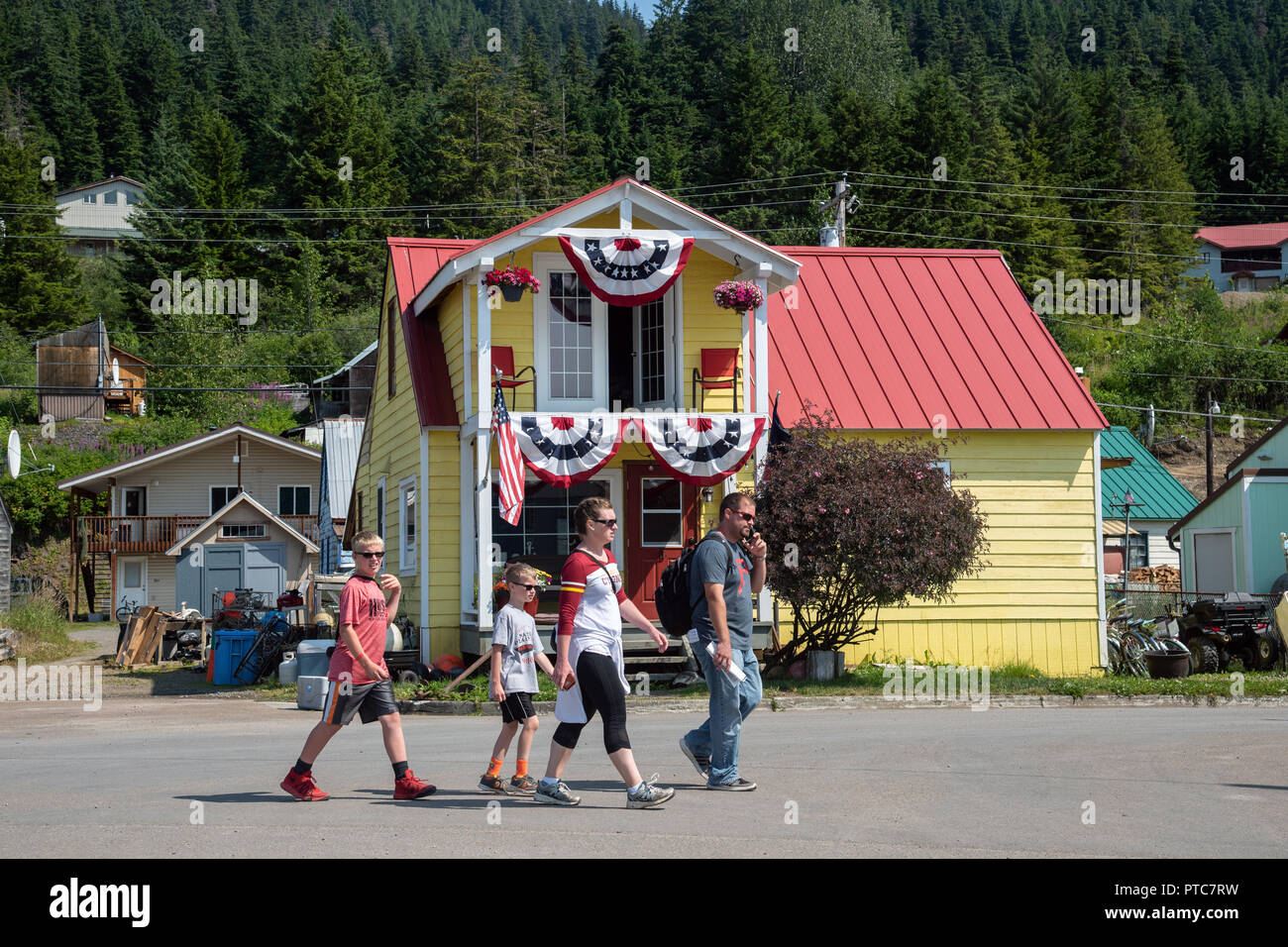 Famille de touristes près de la maison en bois coloré avec drapeaux, Amecan Hoonah, Alaska, USA Banque D'Images