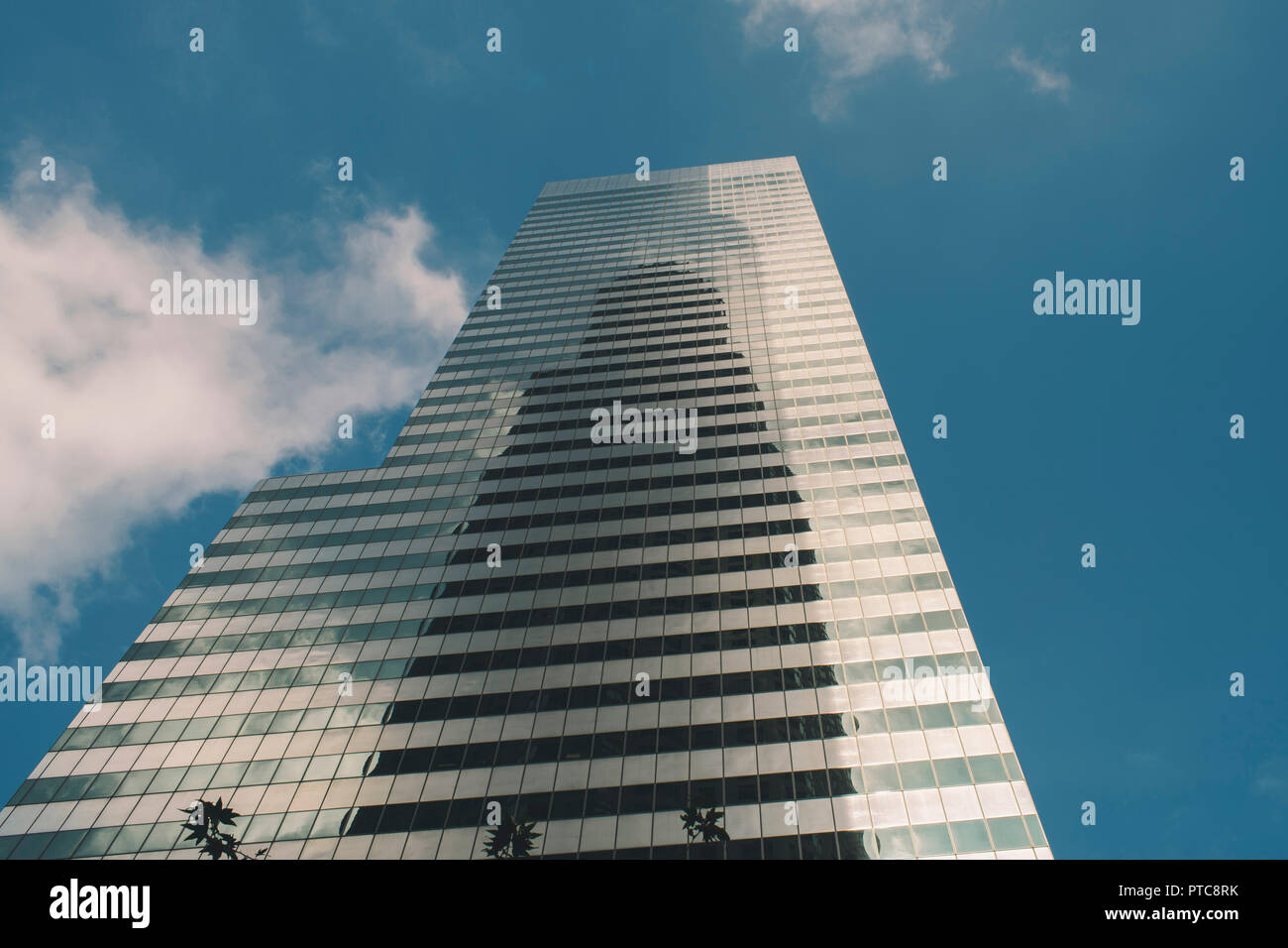 Un racleur de ciel en verre menant au ciel bleu avec des nuages blancs Banque D'Images