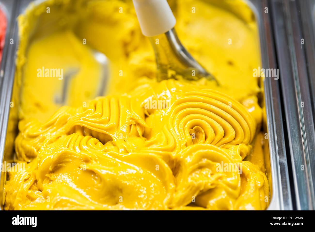 Gros plan macro de saveur mangue orange jaune crème glace gelato avec écope de turbulences sur l'affichage en magasin cafe shop en Italie, l'italien Banque D'Images
