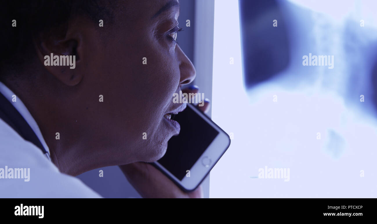 Milieu de MD noir talking on mobile phone avec le patient à propos de x ray Banque D'Images