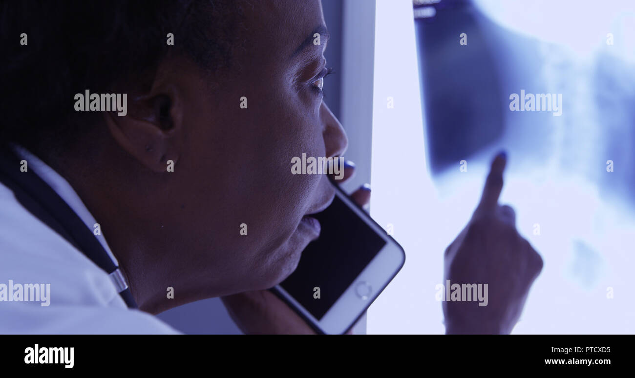 Milieu de MD noir talking on mobile phone avec le patient à propos de x ray Banque D'Images